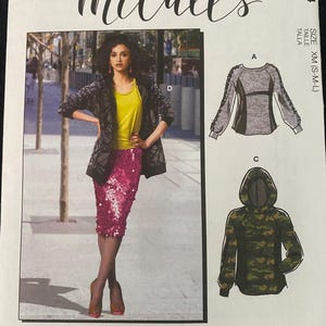 May include: McCall's sewing pattern M8054 featuring a woman in a yellow top, sequined pink skirt, and patterned jacket. The pattern includes options for a long-sleeved top and a camouflage hoodie. The text "#CharlieMcCalls" is also visible.