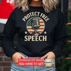 May include: Black sweatshirt with the words "PROTECT FREE SPEECH" surrounding a microphone graphic with an American flag design. The sweatshirt also has two stars on either side of the word "SPEECH".
