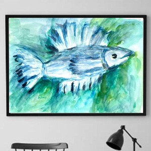 Puede incluir: Pintura a la acuarela de un pez azul y blanco con una aleta grande, sobre un fondo verde y azul. La obra de arte está enmarcada en un marco negro y cuelga de una pared blanca. La habitación también cuenta con una silla negra, una mesa auxiliar y una lámpara.