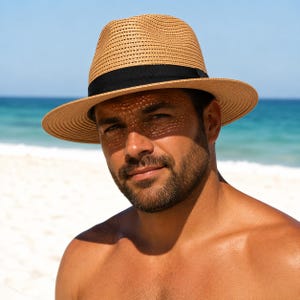 May include: A tan fedora hat with a woven texture and a solid black band around the crown. The hat features a structured brim and a pinched top, providing a classic look. The material appears lightweight and breathable, suitable for sunny weather.
