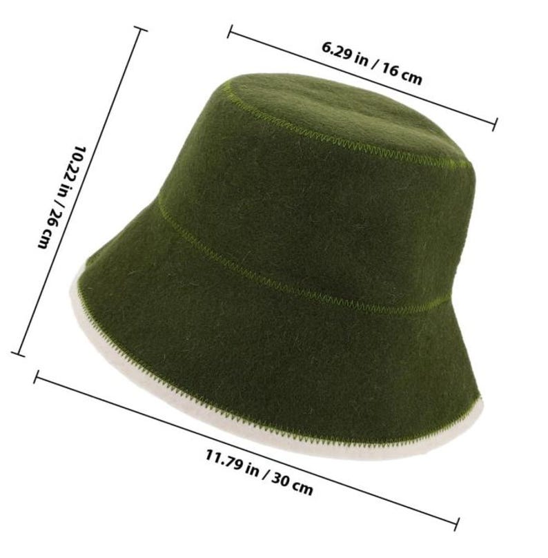 May include: An olive green bucket hat with a white underside and visible stitching. Dimension lines indicate a height of 10.22 inches, a top diameter of 6.29 inches, and a total width of 11.79 inches. The hat features a soft, felt-like texture.