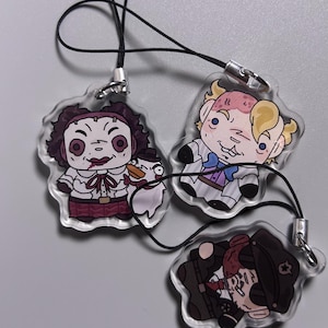 May include: Three clear acrylic charms with cartoon illustrations of characters. One charm features a character in a white shirt and maroon skirt, holding a duck. Another charm depicts a character in a suit. The third charm shows a character in a dark coat.