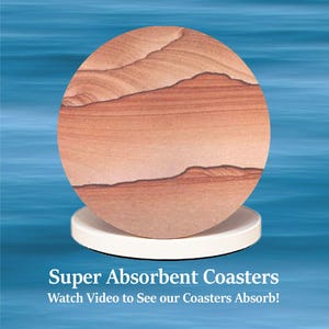 May include: A round, super absorbent coaster with a sandstone design, resting on a white base. The coaster features layers of tan, brown, and reddish-orange hues. Text at the bottom reads "Super Absorbent Coasters" and "Watch Video to See our Coasters Absorb!"
