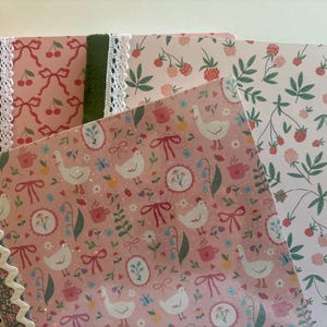 May include: Three rectangular notebooks with patterned covers. One features a pink background with white chickens, red bows, and floral motifs. Another has a white background with red berries and green leaves. The third has a pink cherry pattern.