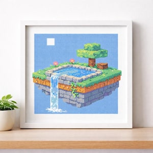 May include: Framed pixel art cross-stitch depicting a floating island with a waterfall, pond, and tree. The artwork features a blue sky background, green grass, and a stone-like structure. Two pink flowers and a small wooden chest are also visible.