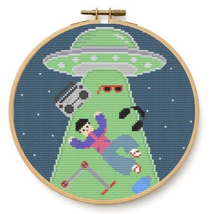 Puede incluir: Un bastidor de bordado circular de madera con un patrón de punto de cruz de un OVNI verde claro abduciendo a una persona con chaqueta morada y pantalones azules. La escena incluye un radiocasete, gafas de sol rojas y un pogo sobre fondo azul.