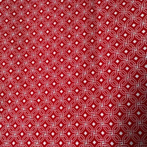 May include: Red fabric with a repeating geometric pattern of white interlocking shapes and diamond accents. The design creates a visually complex and symmetrical arrangement, suitable for various textile applications.