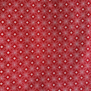 May include: A close-up of a red fabric with a repeating geometric pattern. The pattern consists of white interlocking shapes, including diamonds and octagons, creating a textured design. The fabric has a vibrant, saturated color.