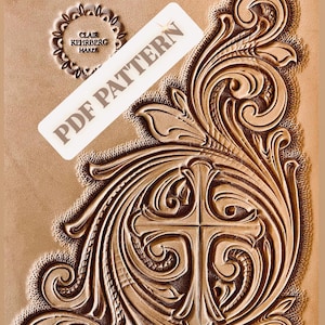 May include: A tan leather craft with an embossed floral design and a cross. The words "PDF PATTERN" are printed on a white label. The text "CLAIR KEHRBERG MAKER" is printed in a circle. The design is a leather craft pattern.
