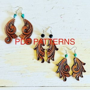 May include: Three pairs of leather earrings with intricate designs. The earrings are brown and feature turquoise and black beads. The earrings are displayed on a white wooden surface. PDF PATTERNS.
