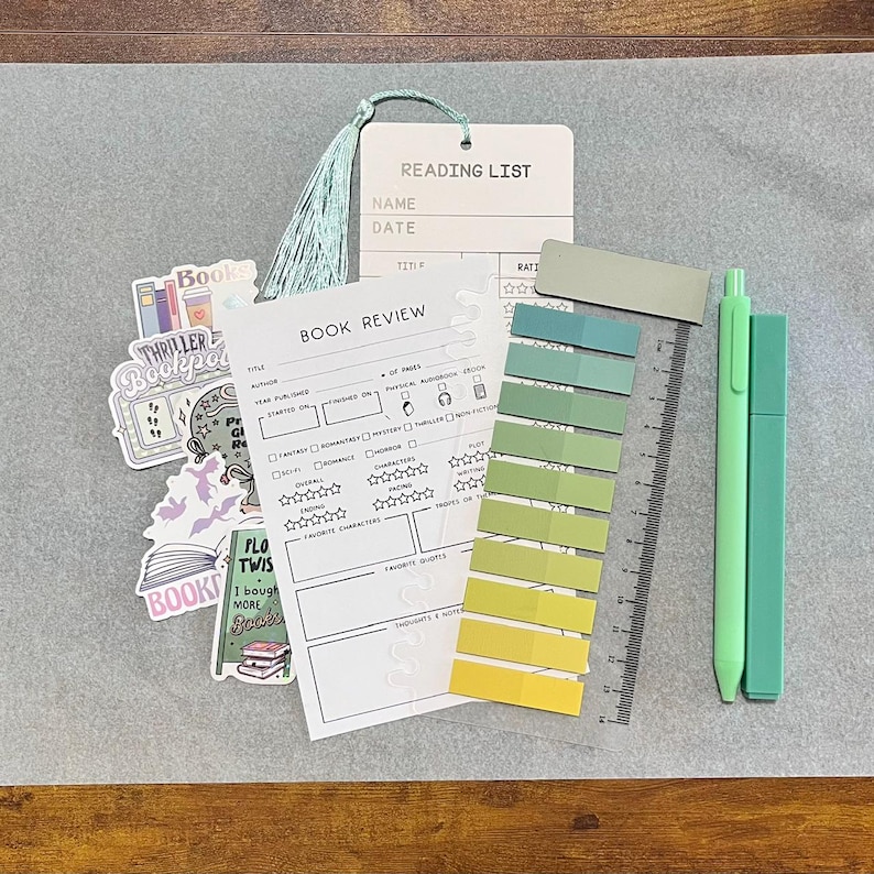 May include: A stationery set including a book review sheet, a book tracker bookmark, a magnetic bookmark, a highlighter, a black gel pen, a colored gel pen, a pack of annotation tabs, and six stickers with text like read, books, and slow burn.