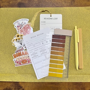 May include: A stationery set including a book review sheet, a book tracker bookmark, a magnetic bookmark, a highlighter, a black gel pen, a colored gel pen, a pack of annotation tabs, and stickers with text like read, books, and slow burn.