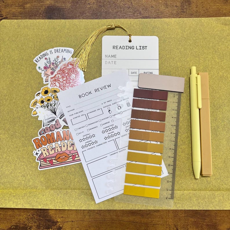 May include: A stationery set including a book review sheet, a book tracker bookmark, a magnetic bookmark, a highlighter, a black gel pen, a colored gel pen, a pack of annotation tabs, and stickers with text like read, books, and slow burn.
