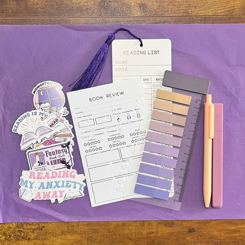 May include: A collection of stationery items including a white book review card, a reading list card with a purple tassel, a set of adhesive page markers in gradient purple shades on a clear ruler, a peach pen, a pink highlighter, and four stickers.