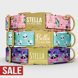 May include: Three personalized dog collars with gold-colored buckles. The top collar is pink with UFO and alien designs, the middle is turquoise with alien faces, and the bottom is purple with astronauts and aliens. Each collar has a name and phone number.