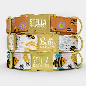 May include: Three personalized dog collars with gold-coloured hardware. The collars feature a repeating pattern of bees, flowers, and honeycomb on a white and orange background. Each collar has a name and phone number.