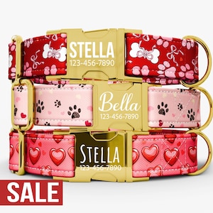 May include: Three personalized dog collars with gold buckles. The top collar is red with white bone and paw print patterns. The middle collar is pink with black paw prints. The bottom collar is red with heart patterns. Each collar has a name and phone number.
