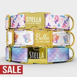 May include: Three personalized dog collars with gold-colored hardware. The top collar has a white background with mermaid and starfish patterns, the middle collar has a white background with mermaid patterns, and the bottom collar has a blue and purple scale pattern. Each collar has a name and phone number.