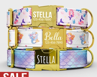 May include: Three personalized dog collars with gold-colored hardware. The top collar has a white background with mermaid and starfish patterns, the middle collar has a white background with mermaid patterns, and the bottom collar has a blue and purple scale pattern. Each collar has a name and phone number.