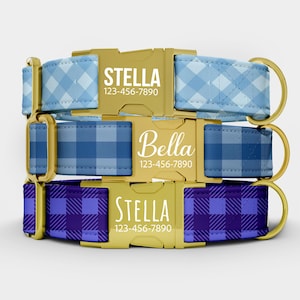 May include: Three dog collars with gold-colored buckles. The collars are patterned in blue and purple plaid. The buckles are engraved with the names "Stella" and "Bella" and a phone number.