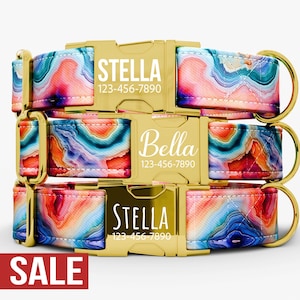 May include: Three stacked dog collars with gold-colored buckles and hardware. The collars feature a colorful, abstract pattern in shades of blue, pink, orange, and green. Each buckle displays a name and phone number in white. The word "SALE" is in a red rectangle.