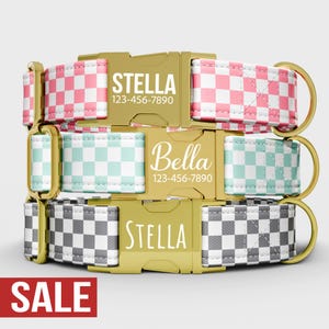 May include: Three dog collars with gold-coloured buckles and D-rings. The collars feature checkered patterns in pink and white, mint and white, and grey and white. Each collar has a name and phone number printed on the buckle.