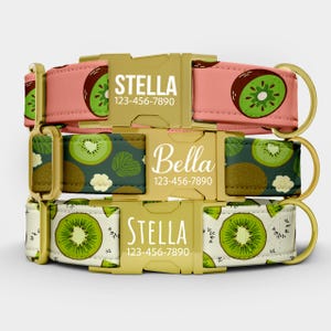 May include: Three dog collars with gold-colored buckles and rings. The collars feature kiwi fruit patterns in pink, green, and white. Each collar has a name and phone number printed on the buckle.