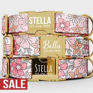 May include: Pink floral dog collars with gold-colored hardware. The collars feature the names "Stella" and "Bella" with phone numbers. The word "SALE" is displayed in a red rectangle at the bottom of the image.