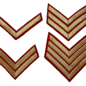 May include: Four red and gold embroidered chevrons, two with a single stripe and two with three stripes. The gold embroidery has a detailed, textured pattern, and the chevrons are arranged in a V-shape.