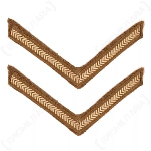 May include: Two brown chevron rank insignia with a light tan herringbone pattern border. The chevrons are angled, with a textured appearance, and are likely military or historical in nature.