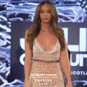 Peut inclure: Une robe longue sans manches en crochet blanc transparent avec un motif ajour&eacute;, un d&eacute;collet&eacute; en V profond et une fine bande horizontale sombre &agrave; la taille. Le v&ecirc;tement pr&eacute;sente un corsage ajust&eacute; qui se prolonge par une jupe fluide et textur&eacute;e.