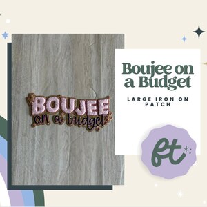 May include: An embroidered iron-on patch featuring the text Boujee on a budget. The word Boujee is in light pink with a dark brown outline, while the words on a budget are in dark brown script. The patch has a textured brown border.