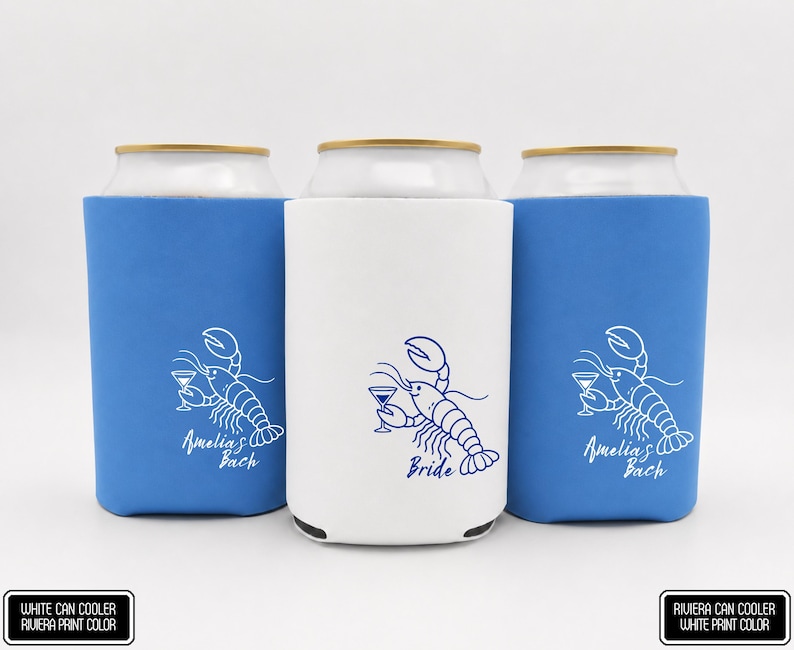 May include: Three foam can coolers, two blue and one white, each featuring a line art illustration of a lobster holding a martini glass. The blue coolers have white text reading Amelia's Bach, while the white cooler has blue text reading Bride.