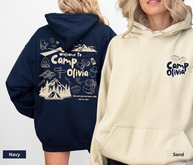Puede incluir: Una sudadera con capucha azul marino con un gr&aacute;fico color crema en la espalda que muestra monta&ntilde;as, una tienda de campa&ntilde;a y el texto "Welcome to Camp Olivia Yellowstone National Park May 11, 2023" y una sudadera color arena con "Camp Olivia" al frente.