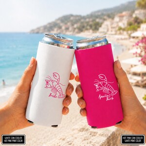 May include: A white can cooler with a hot pink lobster graphic and the text "Bride" and a hot pink can cooler with a white lobster graphic and the text "Amelia's Bach". Both feature a lobster holding a cocktail glass in its claw.