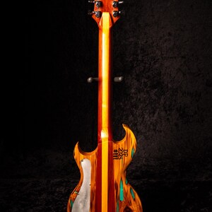 May include: A custom electric guitar with a unique wood grain pattern. The body features a mix of red, orange, and yellow wood, with a silver pickguard and turquoise accents. The headstock and neck are a rich brown.