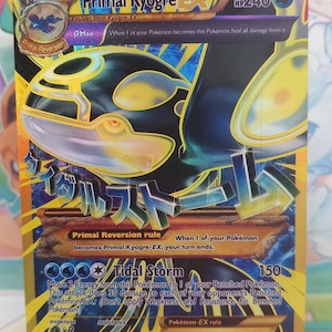 Pode incluir: Um cartão Pokémon Primal Kyogre EX holográfico. O cartão apresenta uma ilustração azul e dourada de Kyogre, com texto japonês. O cartão tem 240 HP e o ataque Tidal Storm.