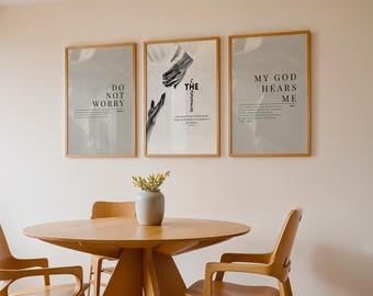 May include: Three framed art prints with inspirational quotes hang above a wooden dining table. The prints feature text that reads "DO NOT WORRY", "THE GOSPEL", and "MY GOD HEARS ME". A vase with greenery sits on the table.