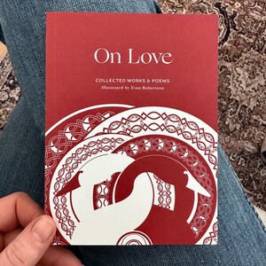 May include: A red book titled "On Love: Collected Works & Poems" illustrated by Evan Robertson. The cover features a white illustration of a stylized bird with a Celtic knot design.