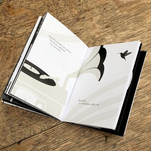K&ouml;nnte beinhalten: Ein offenes Buch mit Schwarzwei&szlig;illustrationen eines Plattenspielers und eines Kolibris. Der Text auf der Seite lautet "Heard melodies are sweet, but those unheard are sweeter. Thereof, as soft pipes play on."