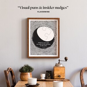 May include: A framed black and white print with a quote about souls being the same. The print features a stylized illustration of a puzzle piece inside a circle. The print is hanging on a light gray wall above a wooden table with a coffee grinder, a potted plant, and two mugs.