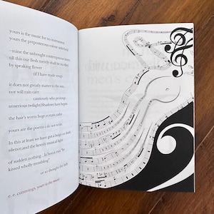 May include: A book with a black and white illustration of musical notes on the right page. The left page features a poem by e. e. cummings titled "yours is the music".