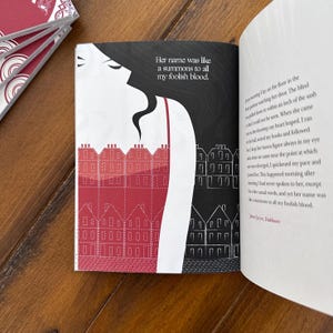 May include: A book cover with a black and white illustration of a woman in a red dress with a row of houses behind her. The text on the cover reads "Her name was like a summons to all my foolish blood."  The book is open to a page with a continuation of the text.