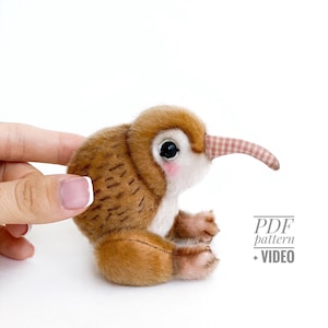 Può includere: Un peluche fatto a mano a forma di kiwi, con pelliccia marrone e beige, un lungo becco a strisce e grandi occhi neri. L'uccello ha piccoli piedi e un rossore rosa sulle guance. Il testo recita "PDF pattern + VIDEO".