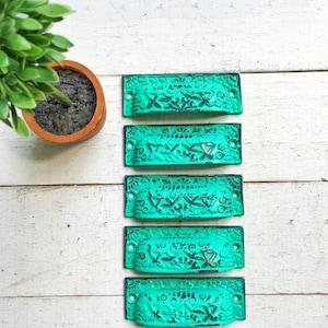 May include: Seven turquoise blue drawer pulls with intricate designs. The pulls are made of metal and have a distressed finish.