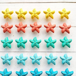 May include: A set of 20 ceramic starfish drawer pulls in various shades of yellow, orange, blue and turquoise. The starfish are arranged in four rows of five, with the colors gradually transitioning from yellow to turquoise.