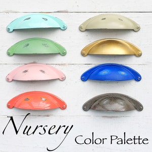 May include: A nursery color palette with eight different colored cabinet knobs. The colors are light blue, green, pink, orange, gold, gray, blue, and light green.