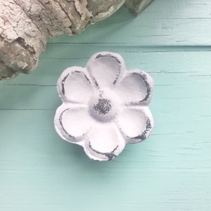 May include: White ceramic flower-shaped drawer pull with a distressed finish. The pull has five petals and a center knob.