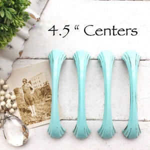 May include: Four turquoise blue cabinet pulls with a distressed finish. The pulls are 4.5 inches apart.