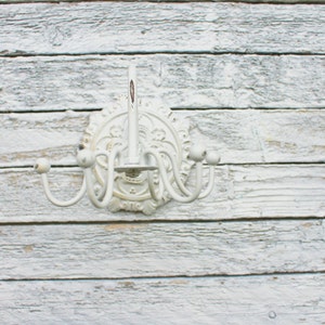 May include: White metal wall mounted coat rack with a decorative floral design and five hooks.